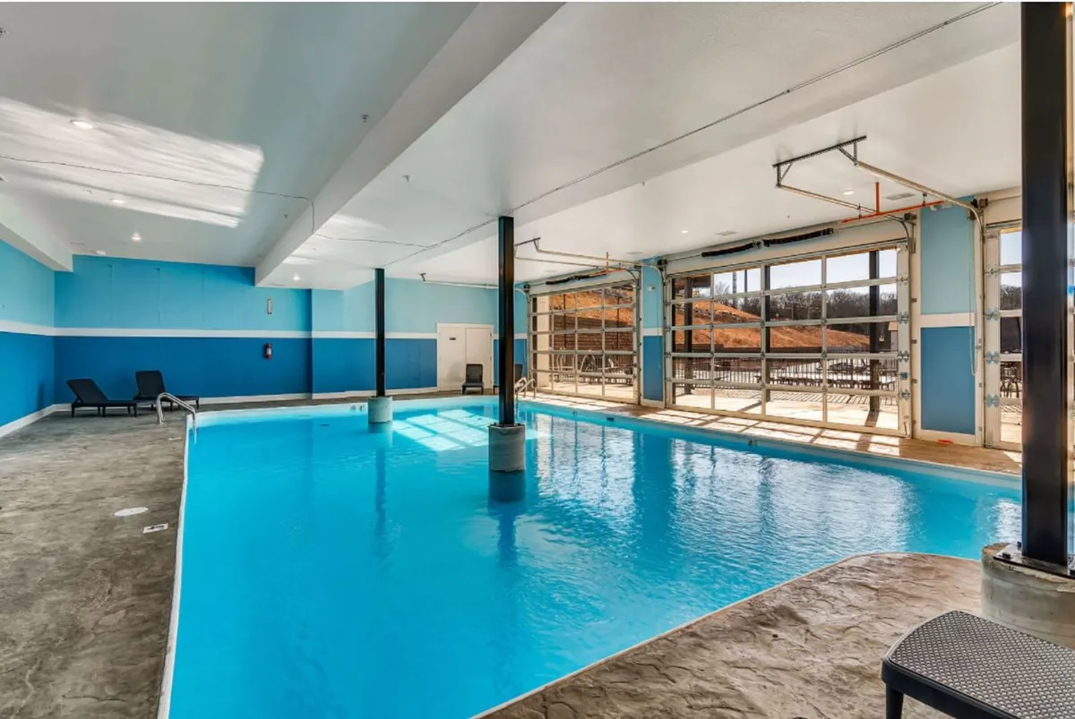 An inviting indoor swimming pool with large glass doors letting in natural light. Comfortable seating lines the pool area, and the space is calm and family-friendly, perfect for relaxing together after a busy day of exploring the city.