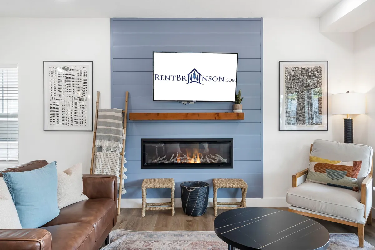 A spacious, comfortable family room featuring plush seating arranged around a fireplace and a large TV. The decor is warm and inviting, with artwork on the walls and soft lighting, ideal for movie nights and socializing.
