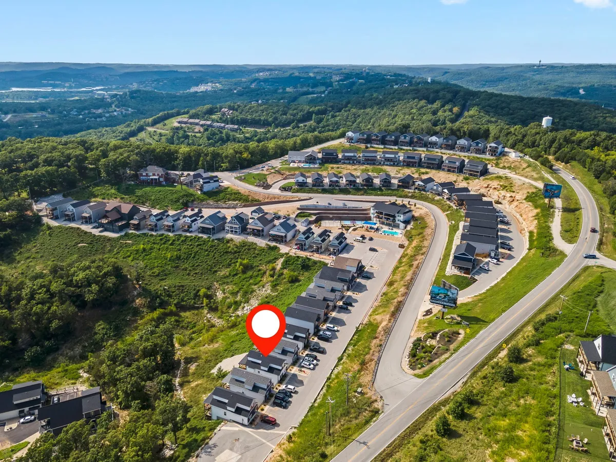 A welcoming exterior image of newly constructed homes winding along a curved road, set against a green hillside. The community layout is visible, hinting at both scenic views and easy access to outdoor attractions and neighborhood events.