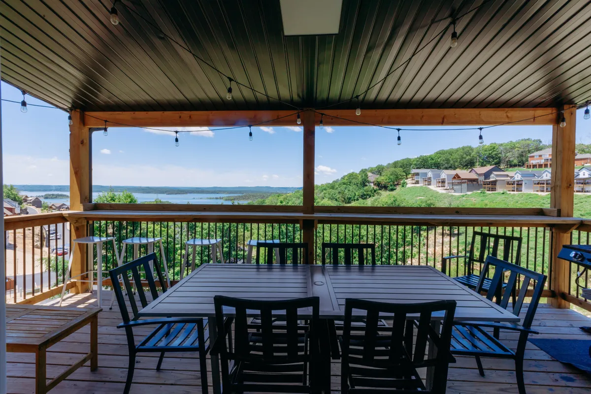 An inviting outdoor dining area with a table set against a backdrop of lake views and lush greenery. The scene is comfortable and welcoming, perfect for relaxing with family or friends while enjoying the sunset or sunrise.