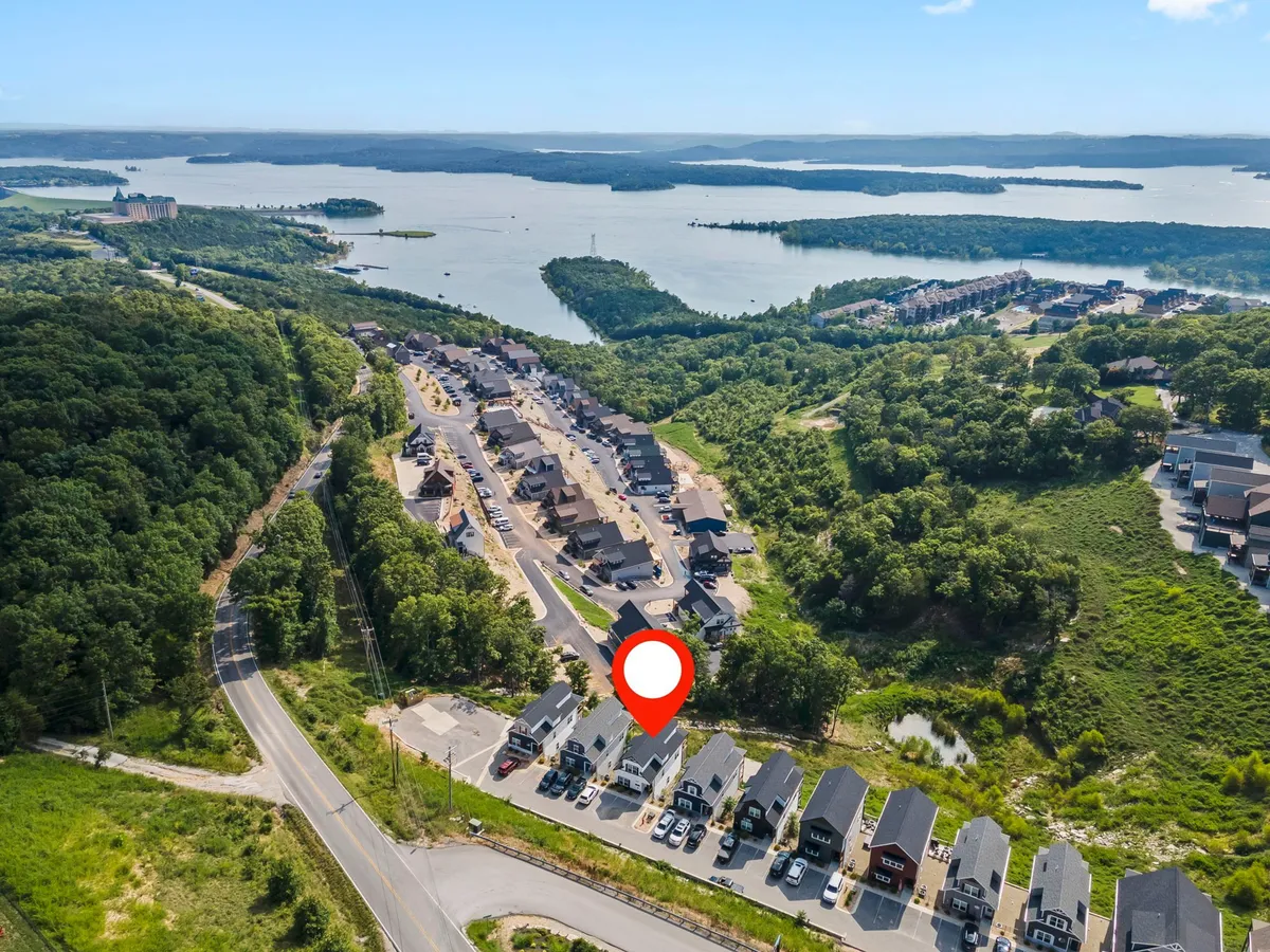 A tranquil waterfront view of a residential community, surrounded by greenery and calm lake waters. The wide open spaces are ideal for morning walks by the water and enjoying nature with a pet.