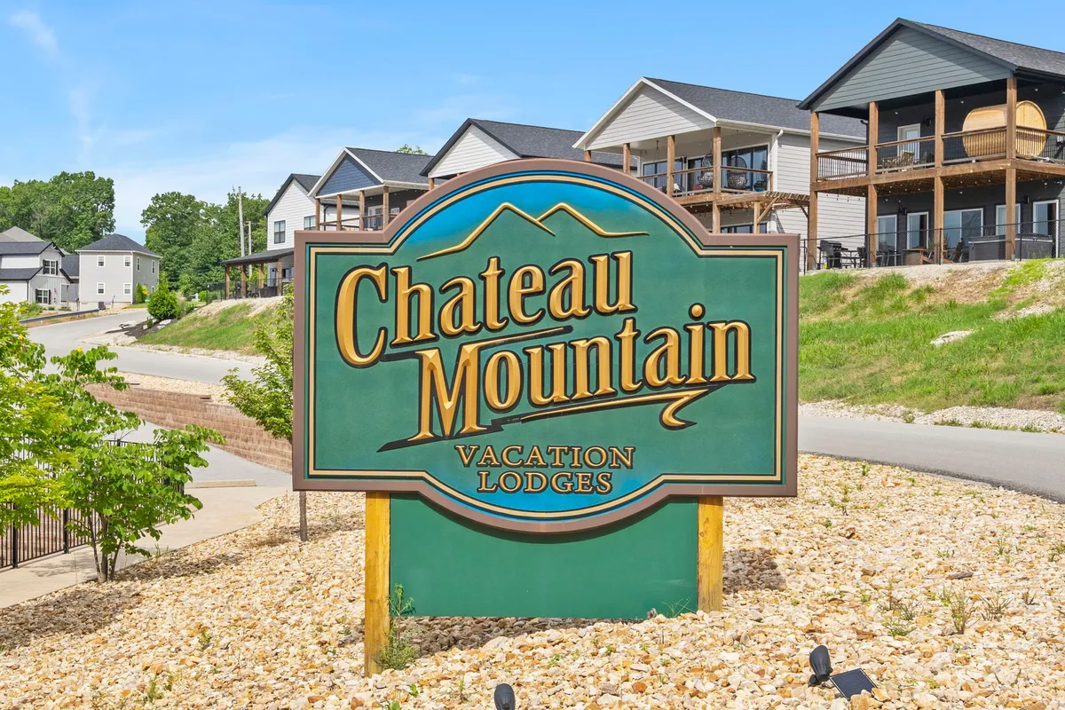 The Chateau Mountain sign is prominently displayed, surrounded by landscaped grounds and neighboring lodges. The scene is inviting, with plenty of open, grassy areas, suggesting spaces for walking or relaxing outdoors with a pet.